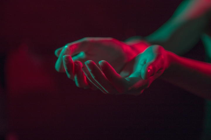 photo of two hands held open and bathed in green and red highlights