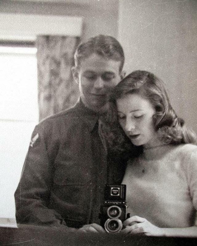 Black & white of a couple in the 1940s taking a selfie in a mirror
