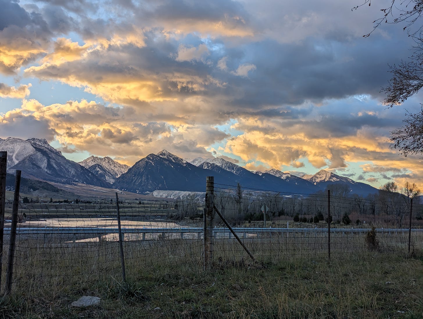 Early winter sunrise lights up clouds over the Absaroka range, Yellowstone River foreground