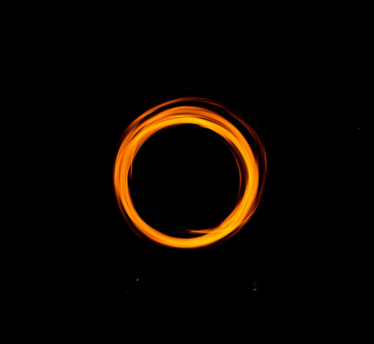 A ring of orange light stands stark against a black background. 