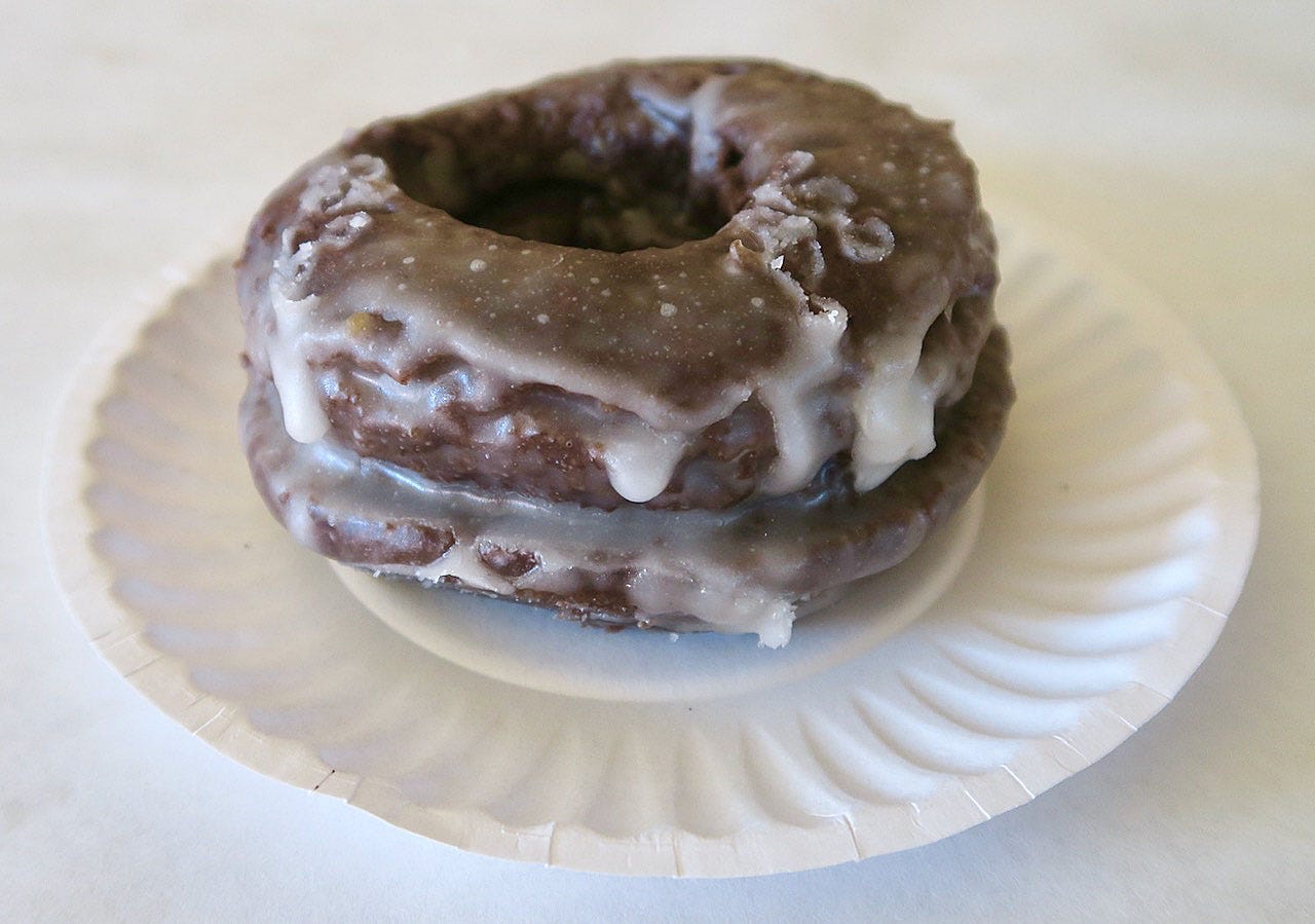 A chocolate donut with icing on top

Description automatically generated