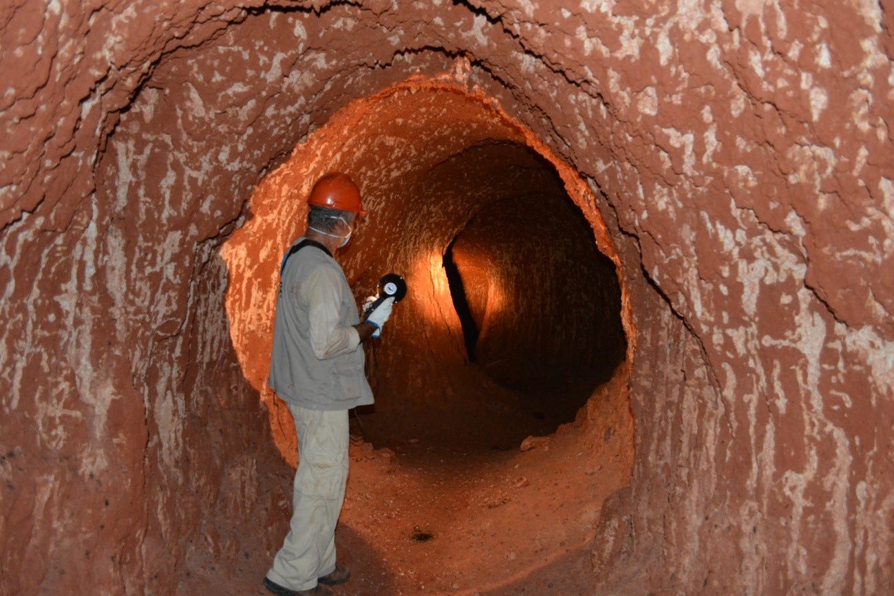 A man in a hard hat is stood upright with room to spare in a paleoburrow