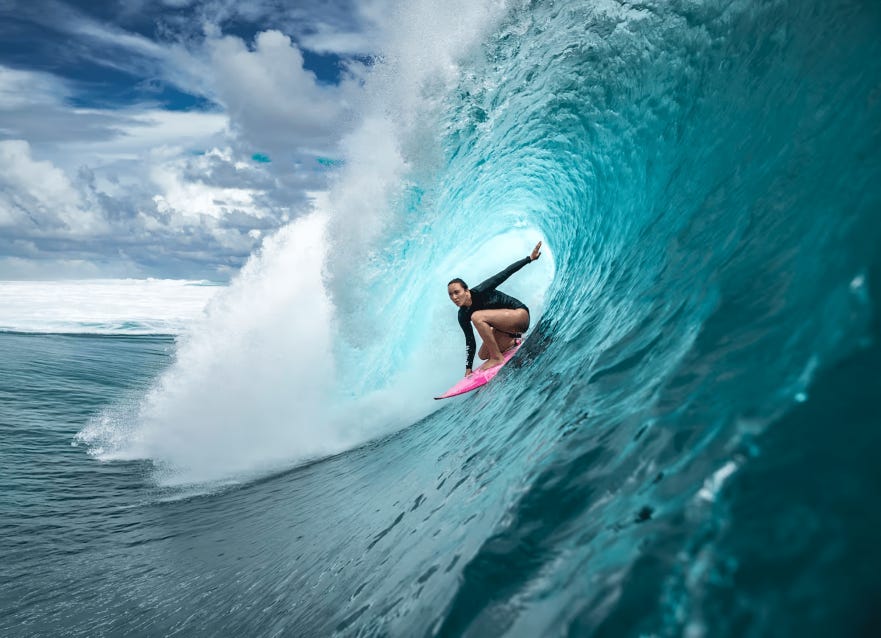 Young female surfer riding a large barrel wave in clear turquoise waters, showcasing skill and thrill in extreme sports.