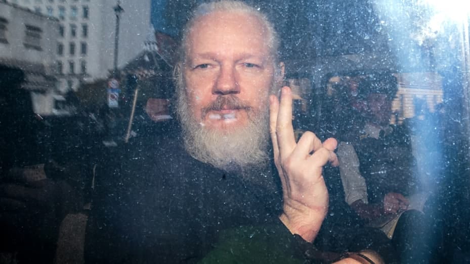 Julian Assange gestures to the media from a police vehicle on his arrival at Westminster Magistrates court on April 11, 2019 in London, England.