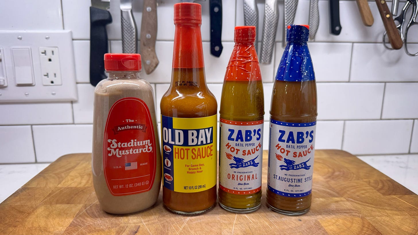 From left to right bottles of Authentic Stadium Mustard, Old Bay Hot Sauce, and Zab's Original and St. Augustine-style Datil Pepper Sauces