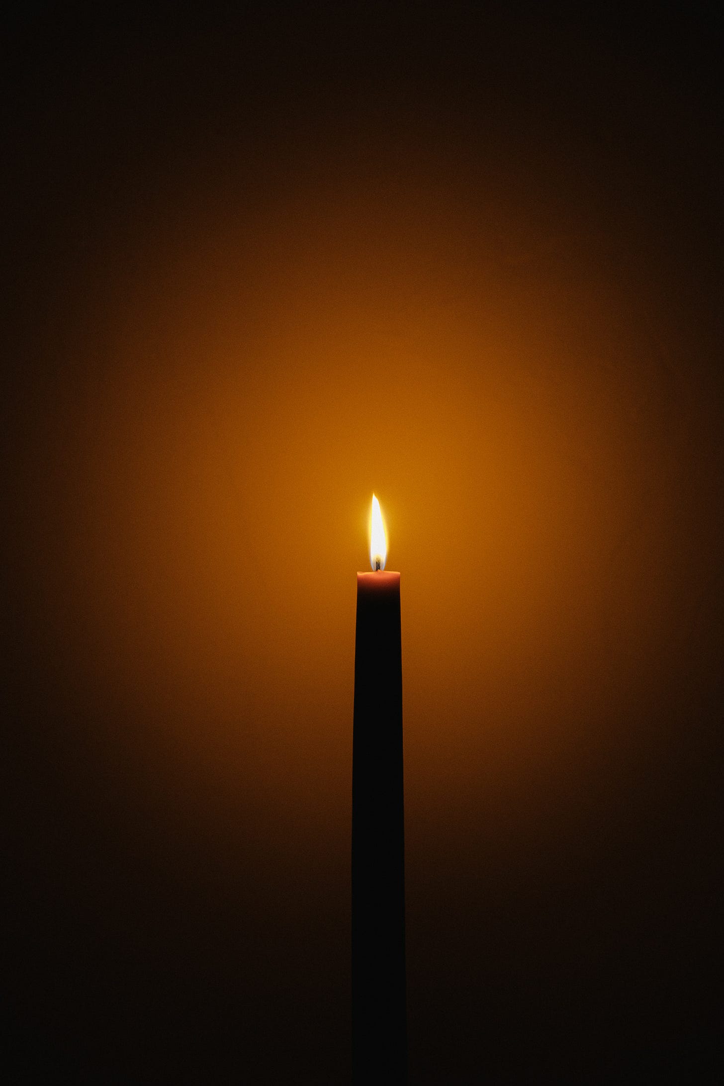 the warm glow of a lit candle against a wall