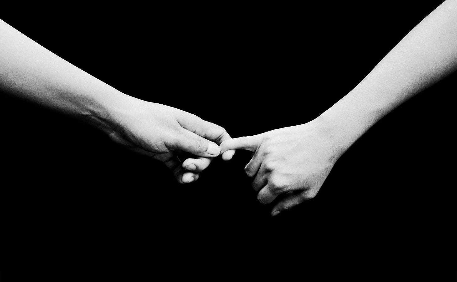 two hands lighting holding each other over a black background