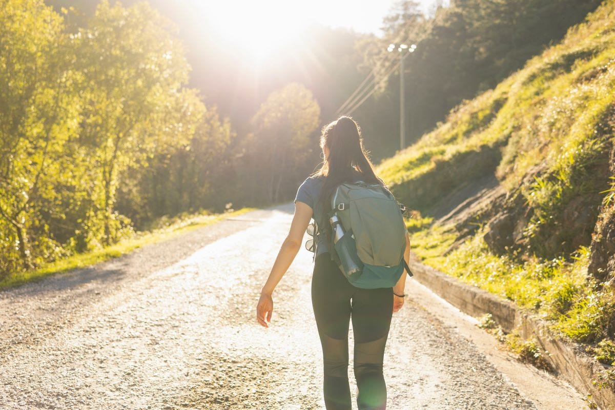 Woman hiker on forest road with backpack