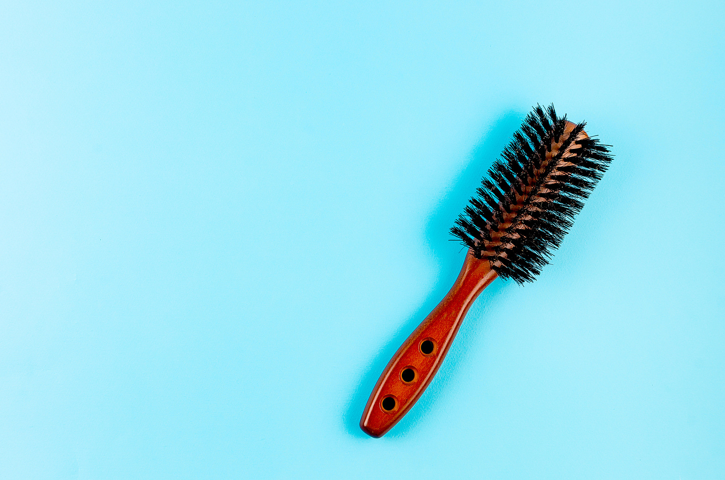 Wooden hairbrush with natural boar bristles on blue background