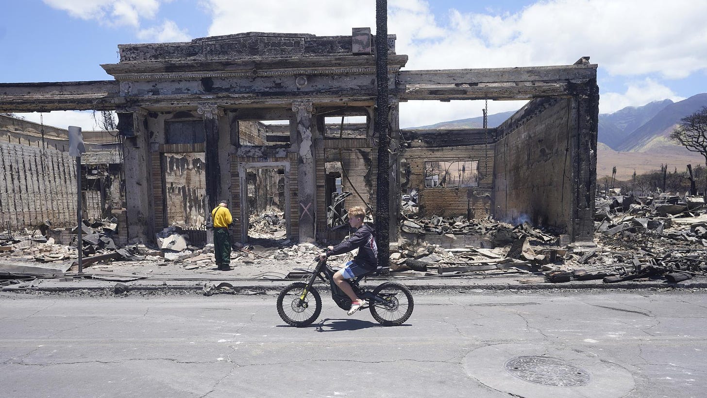A boy rides along Main Street past wildfire damage.