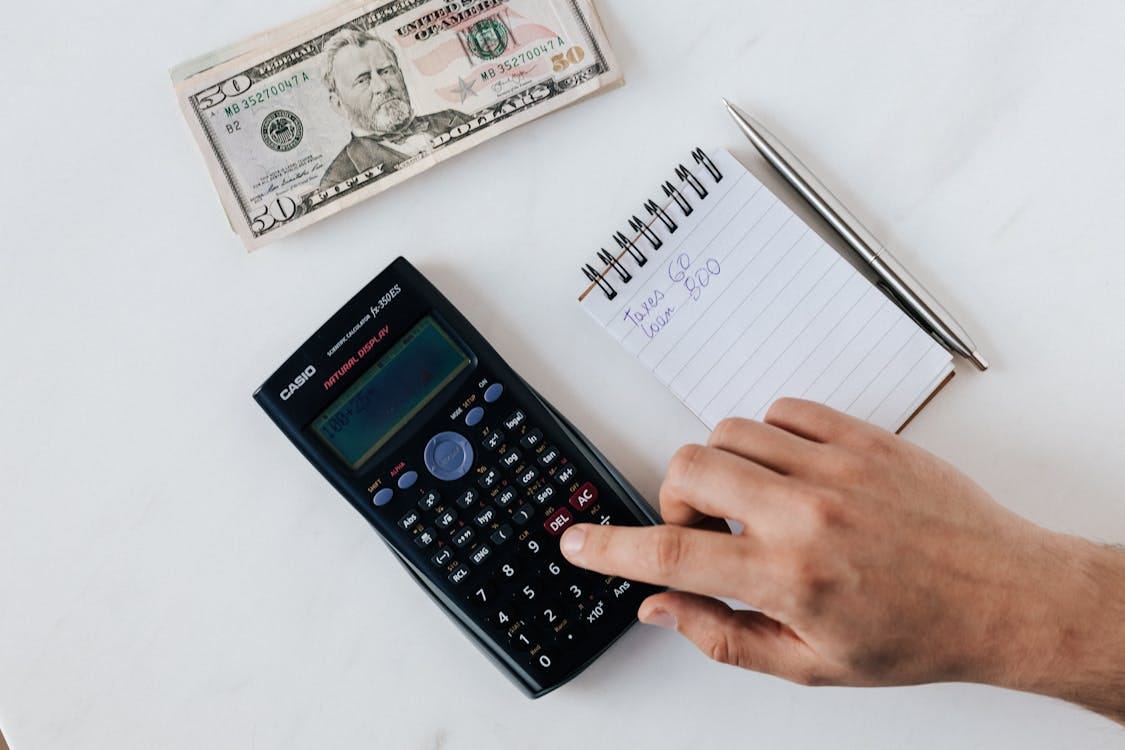 Free Crop faceless accountant using calculator while making budget Stock Photo