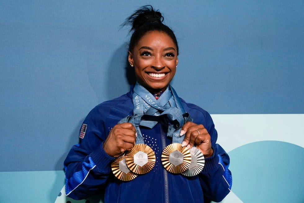 Simone Biles posing with her 3 Gold medals and 1 Silver medal in Paris. (AP Photo/Charlie Riedel)