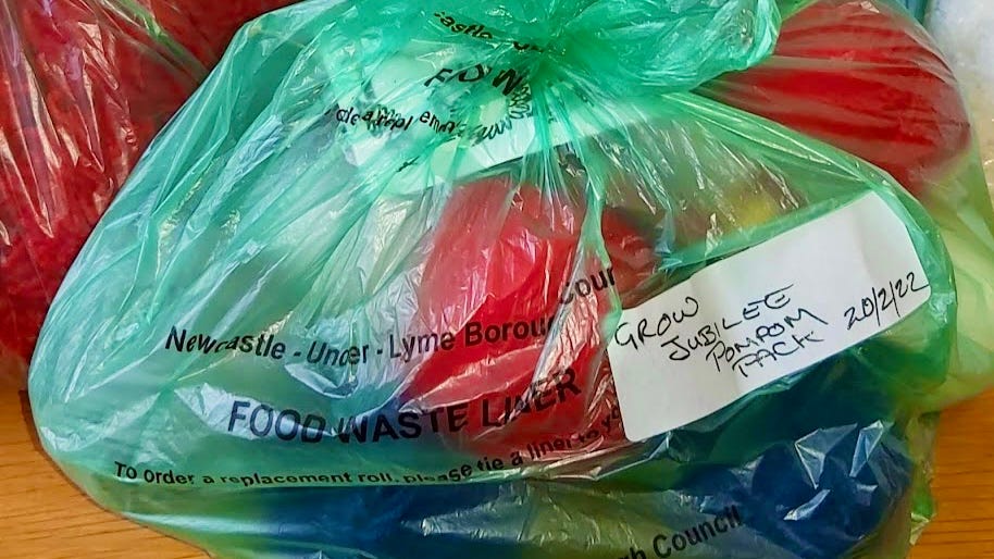 a green plastic bag stuffed full of woolly pompoms