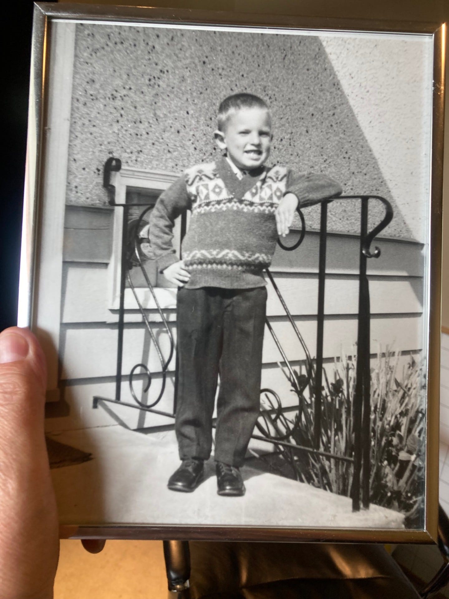 The author as a young boy in a black and white photograph.  He stands somewhat rigid on a set of steps in front of a stuccoed house.