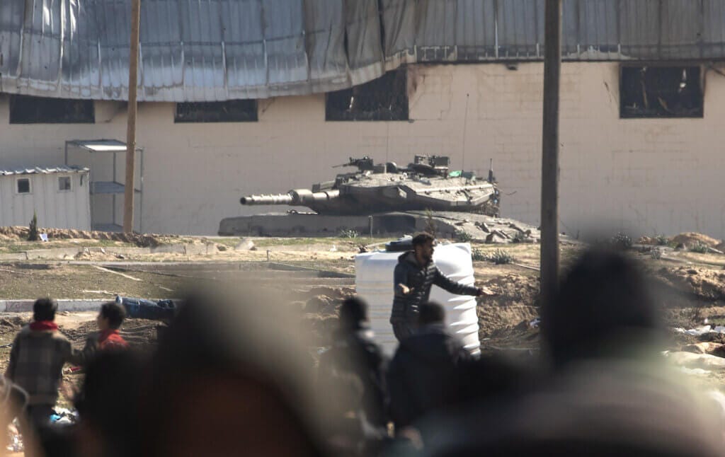 Displaced Palestinians flee past Israeli tanks following military orders to leave Khan Younis and go toward Rafah near the Egyptian border in the southern Gaza Strip, January 26, 2024. (Photo: Haitham Imad/EFE via ZUMA Press APA Images)