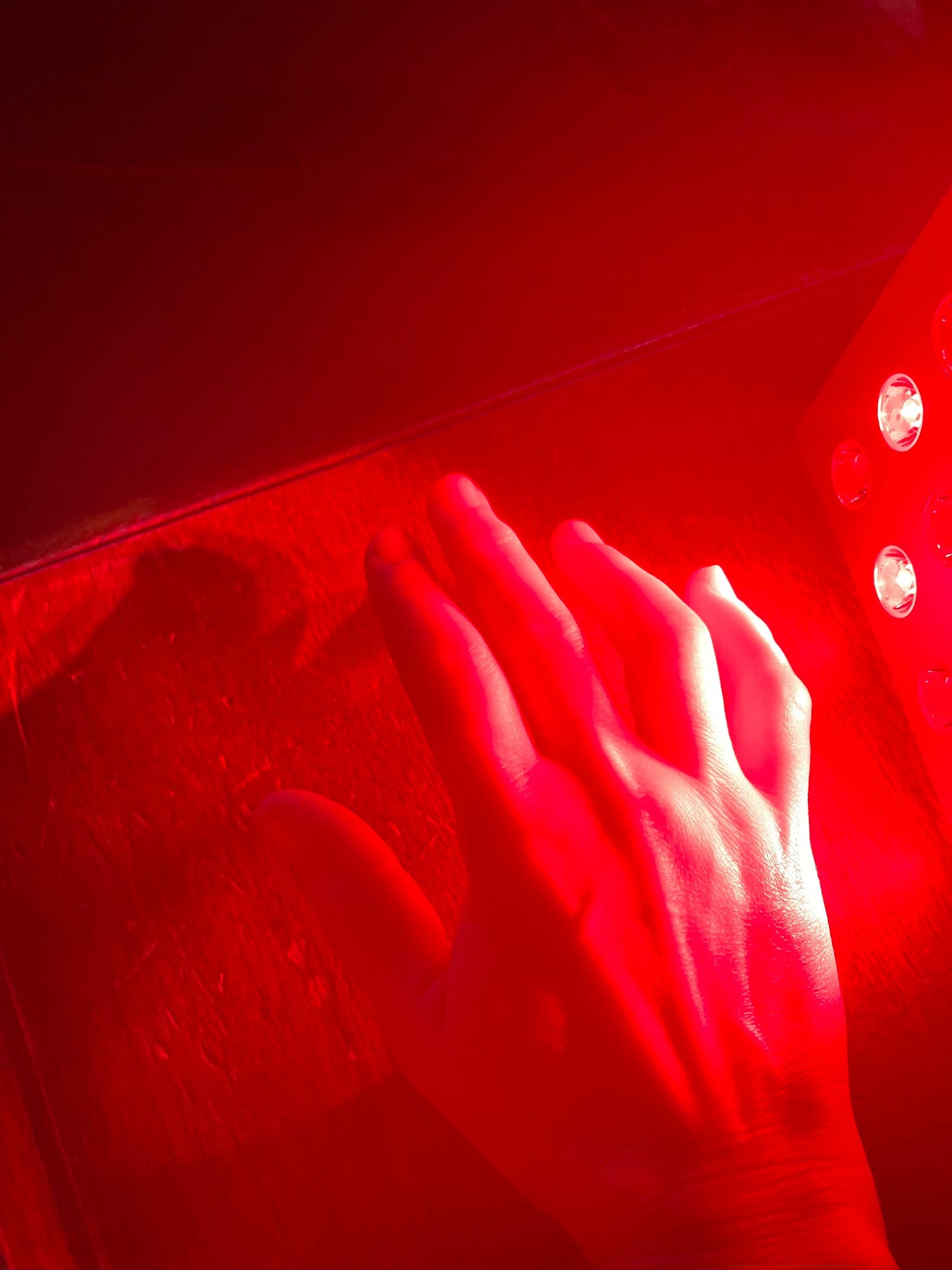 hand in front of a red light therapy unit