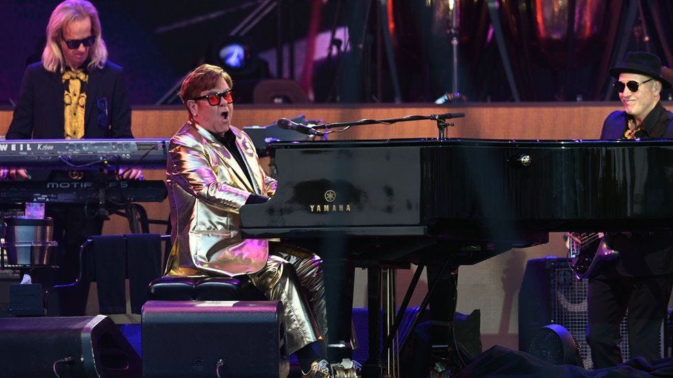 Elton John hammering away on a piano at Glasto