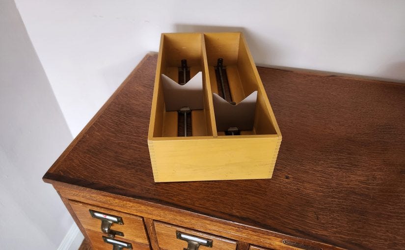 Library charging tray with two rows for storing 3 x 5" index cards in portrait orientation. It's sitting on a small library card catalog.