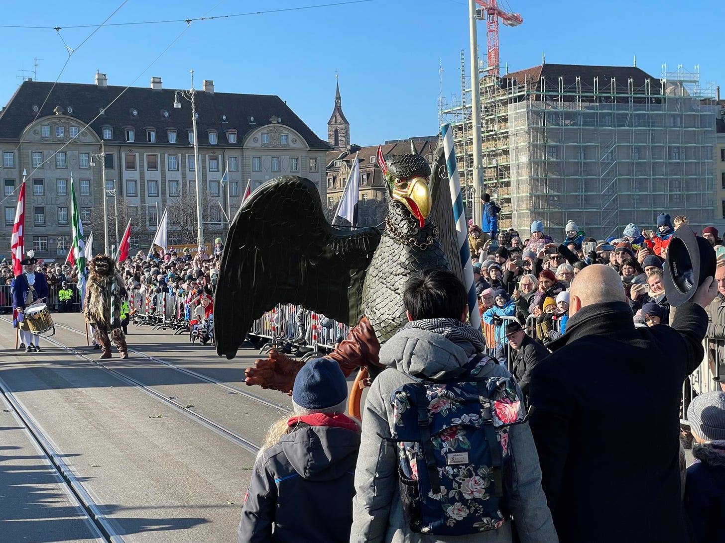 Person wearing a golden beaked griffin costume with wings faces a man doffing his hat.