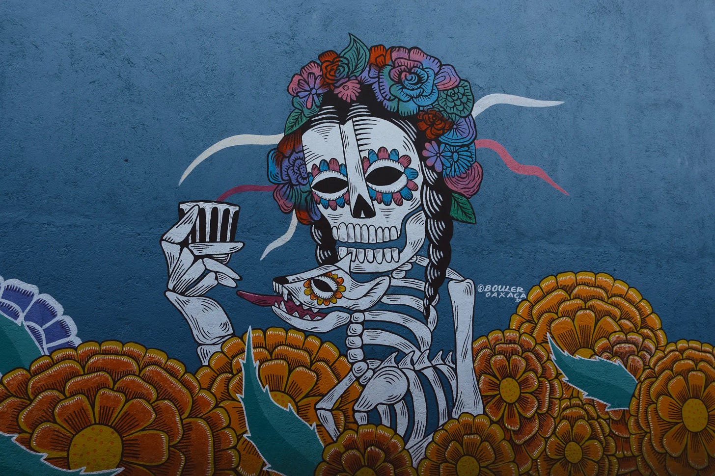 A mural of a skeleton drinking mezcal