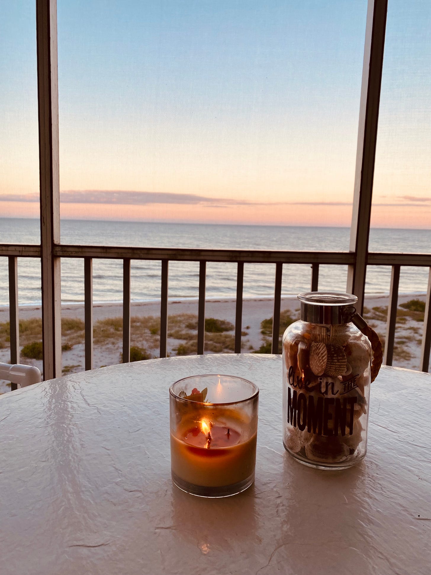 Ocean view from balcony with burning candle and jar of seashells