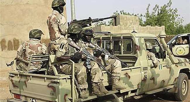 A file photo of Nigerian soldiers sitting on a military pick-up truck at a military base.