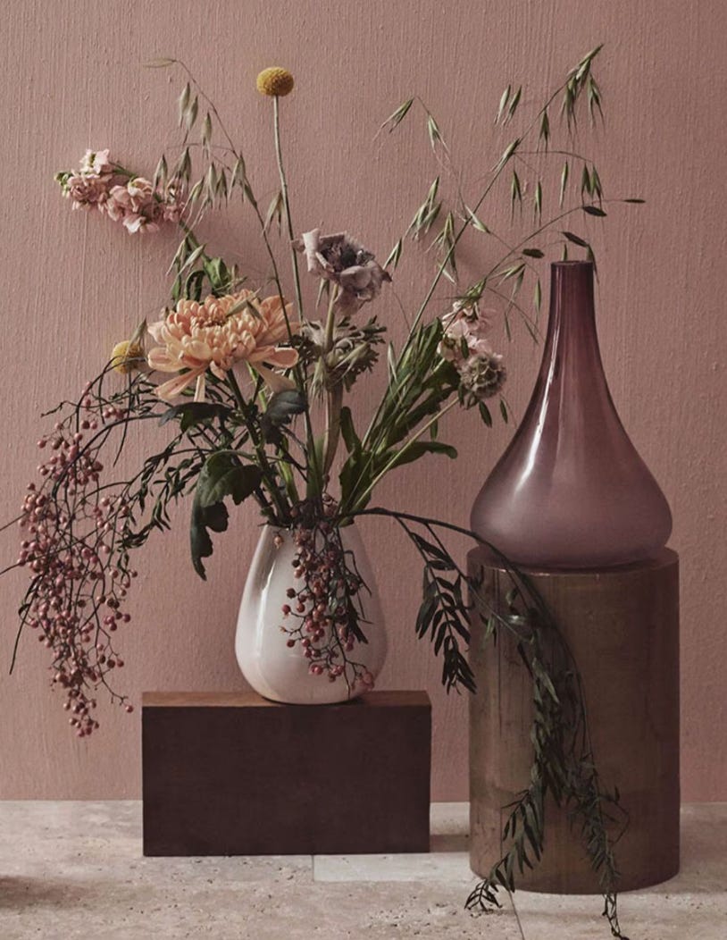 still life of flowers in a vase against a mauve wall, in tones of mauves