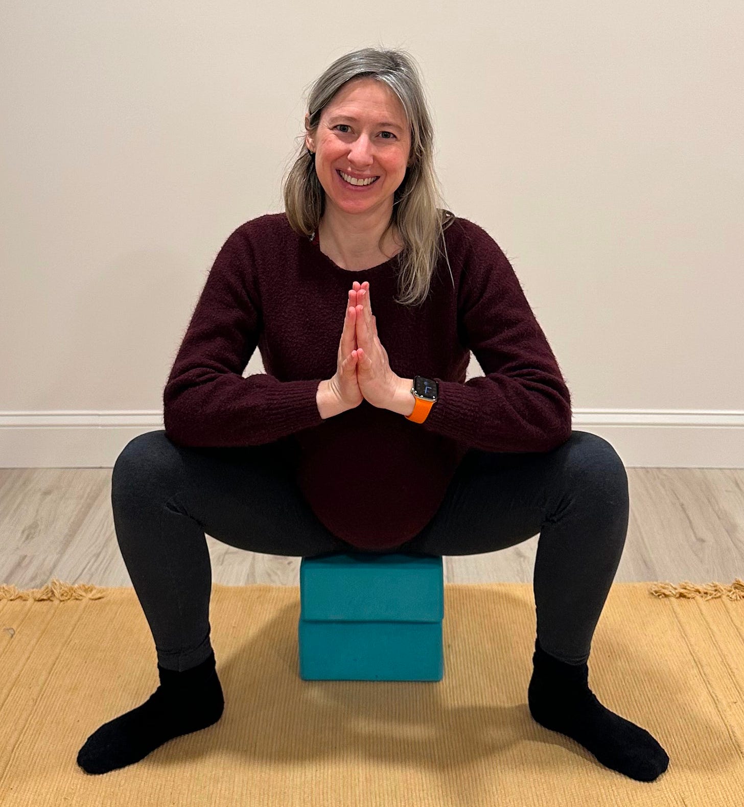 Woman squatting low in a yoga pose called Yogi Squat