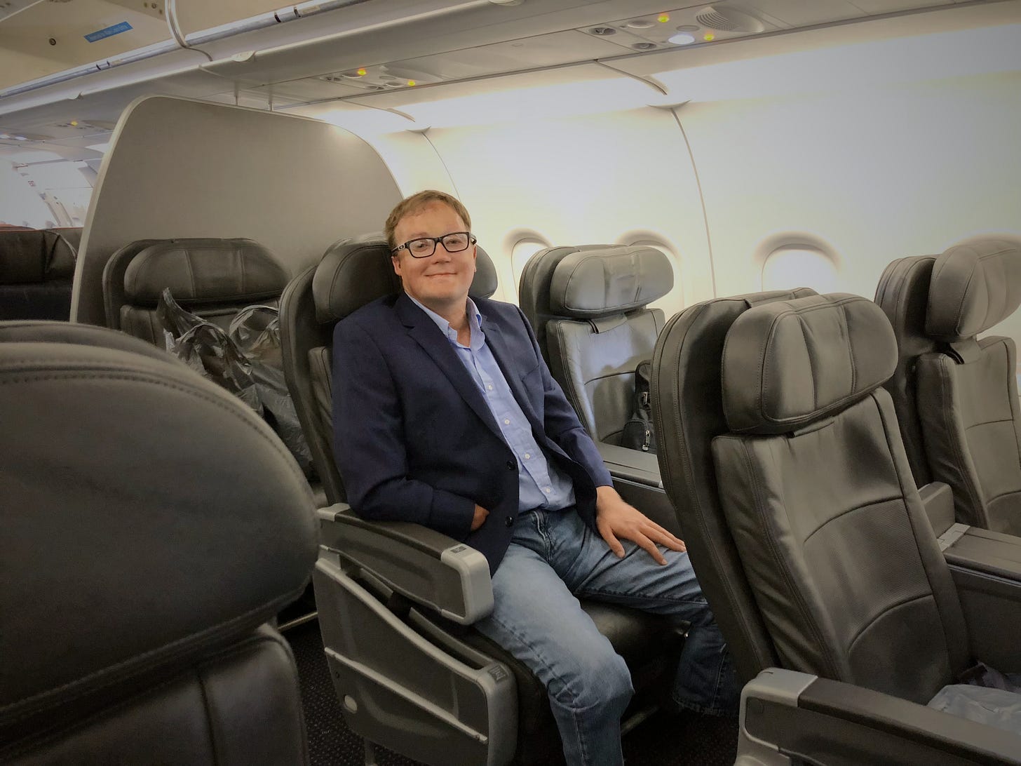 John seated in an airplane seat as the last passenger onboard the plane.