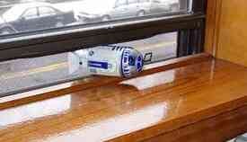 An R2-D2 toy is on its side, wedged to keep a window open.