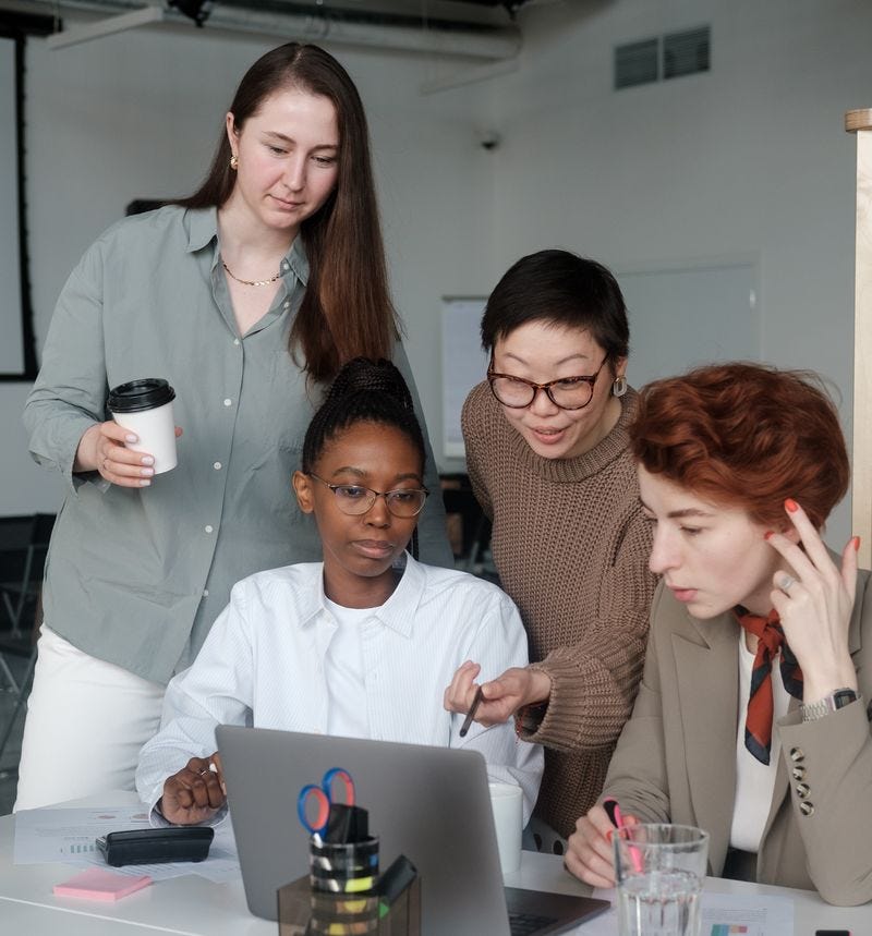 Photo of four people discussing what's on a laptop screen 