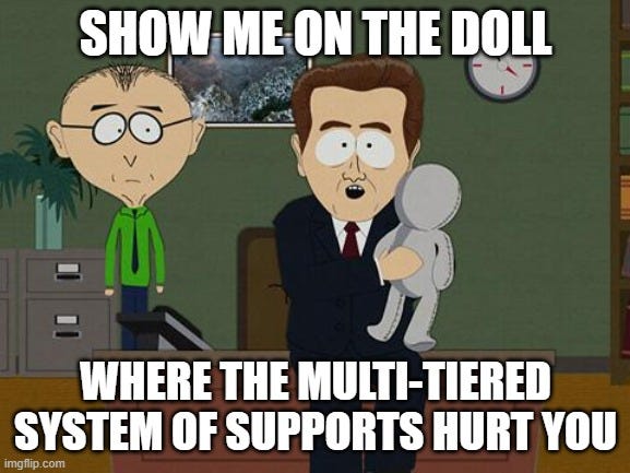 South Park teacher stands beside man in suit, who holds a doll. He's saying "Show me on the doll where the multi-tiered System of Supports hurt you"