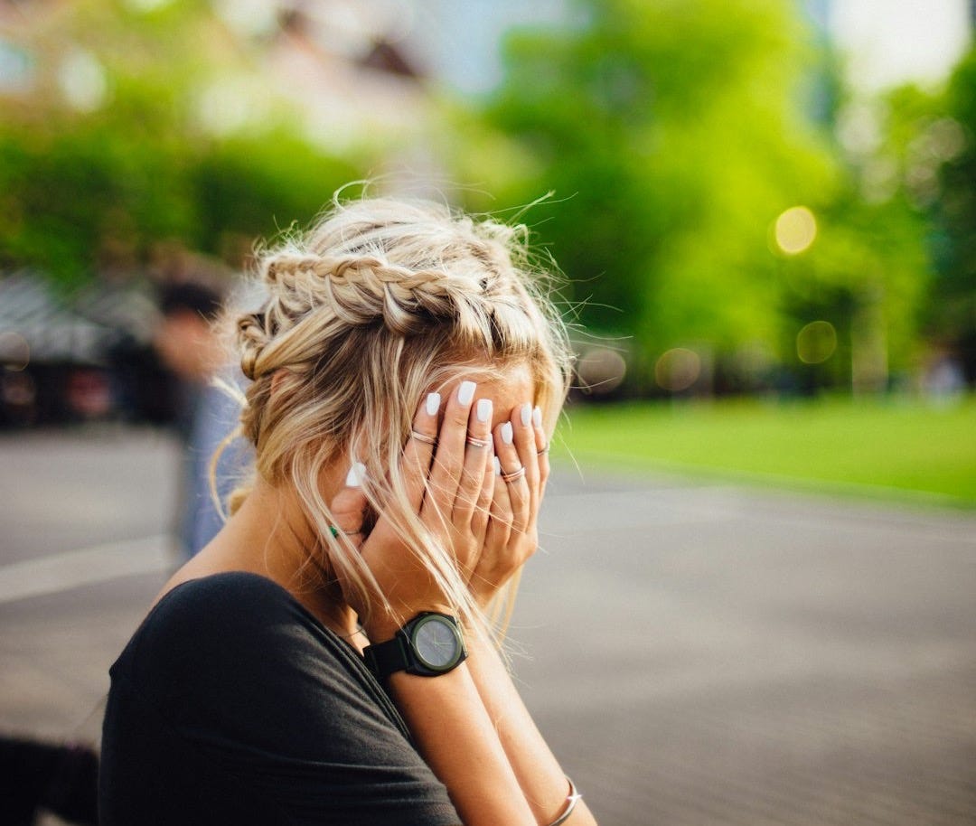 person covering face with hands outdoors person covering face with hands outdoors