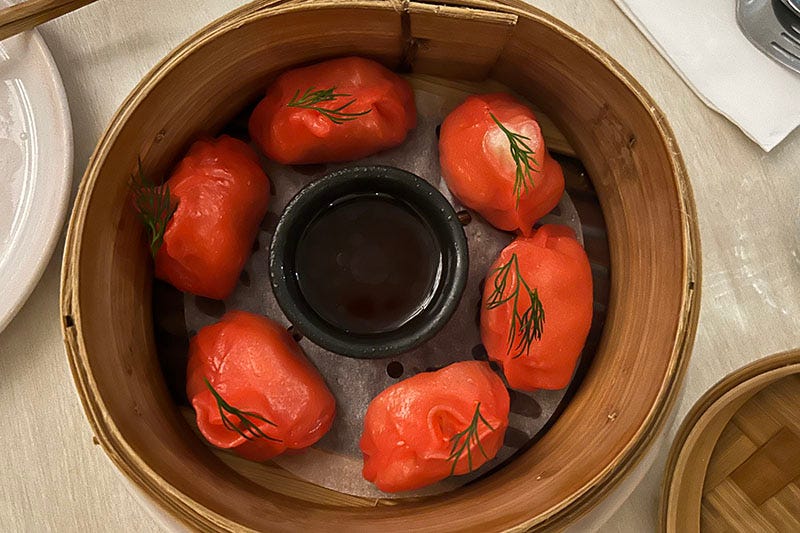 Red dumplings in a bamboo steamer.