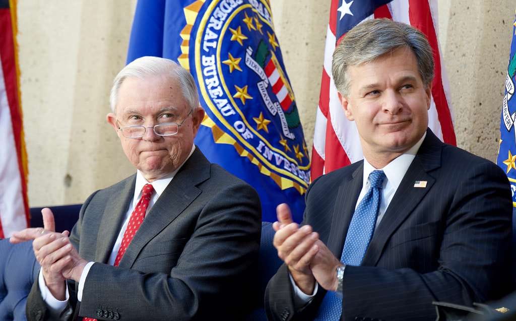 A gray-haired man clapping, sitting next to a white-hard man with glasses, also clapping