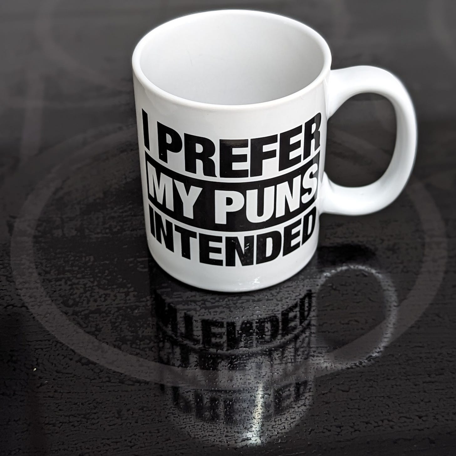 A coffee mug that says "I prefer my puns intended"