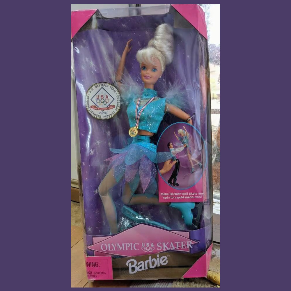 Olympic Skater Barbie in a box with a blonde hair, a blue sparkly outfit, ice skates and a gold medal
