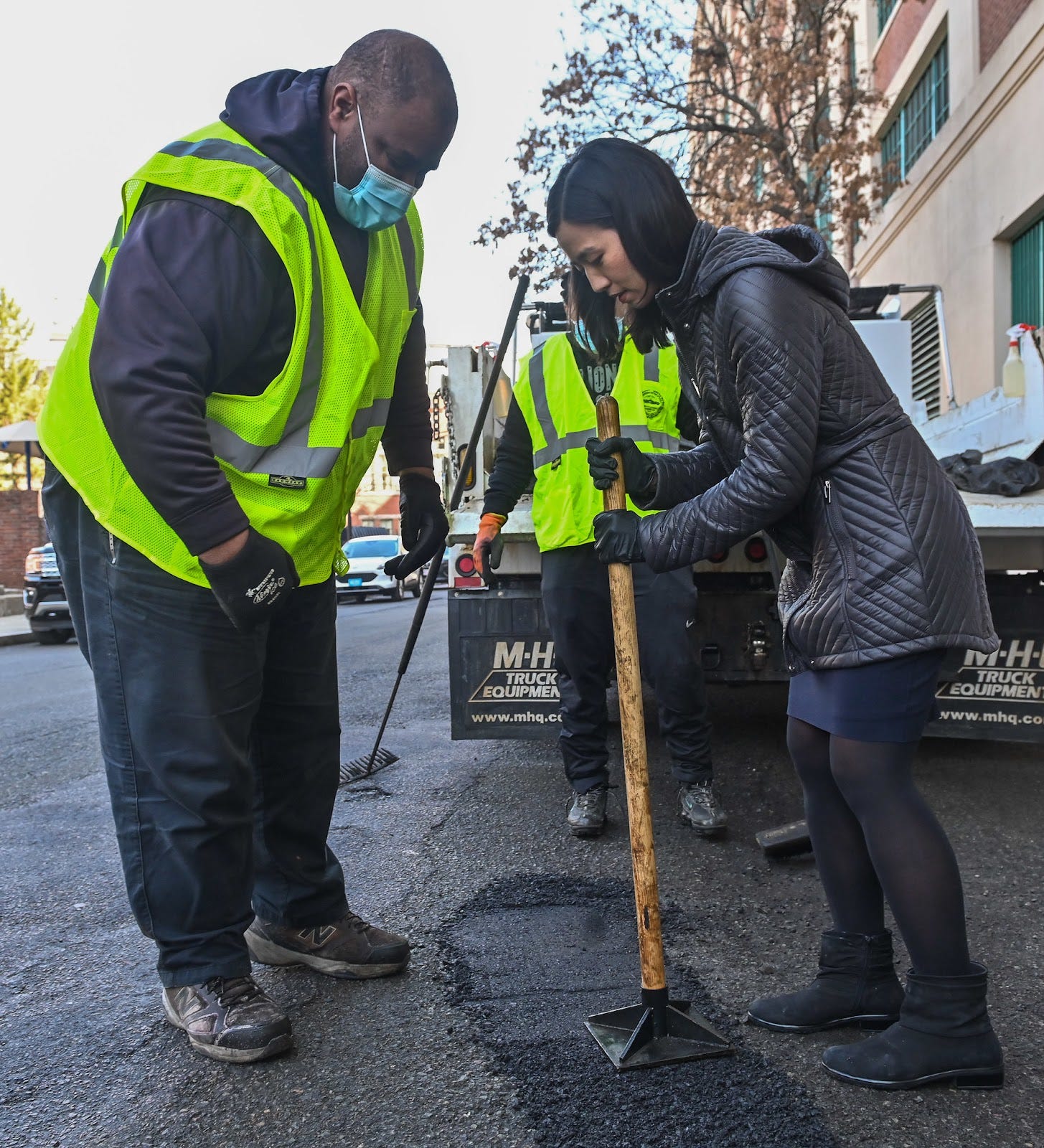 Michelle tamps down the asphalt inside the pothole with help from a Public Works team member