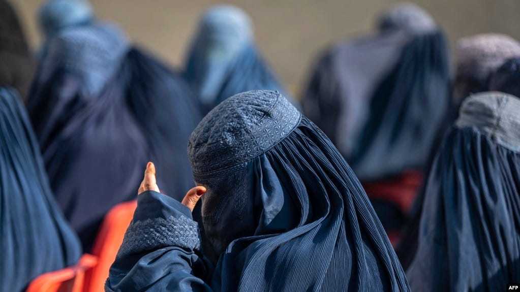 Afghan burqa-clad women sit as they wait to receive cash money being distributed as an aid by the World Food Programme organisation in Pul-i-Alam, the provincial capital of Logar Province on January 7, 2024. (Wakil KOHSAR / AFP)