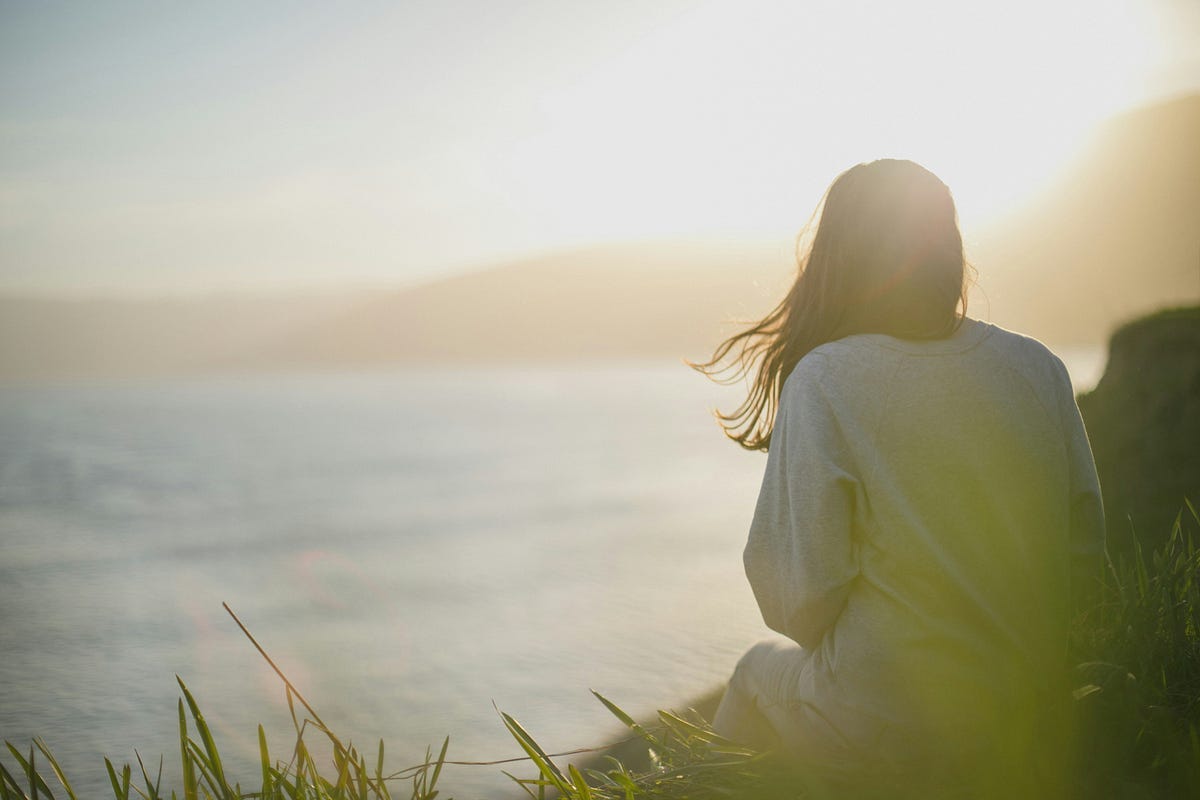 Woman sitting and looking out at sea.