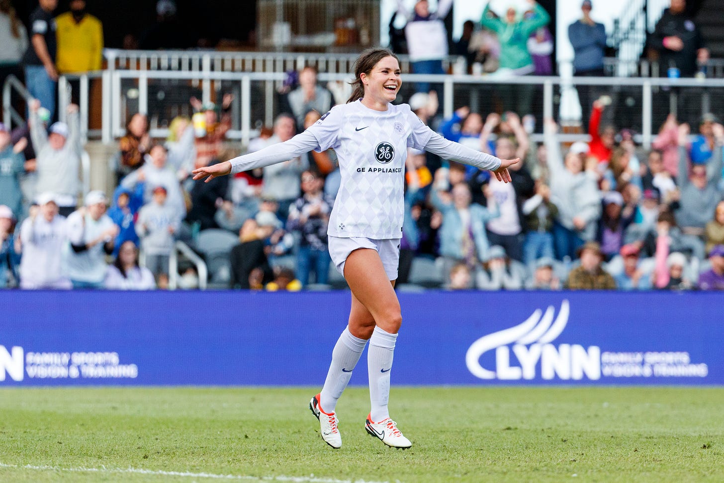 Player in purple and white uniform with arms outstretched facing right