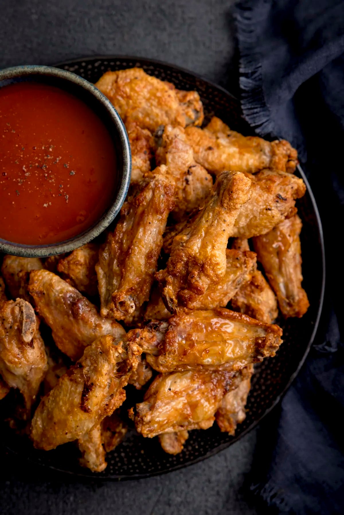 Crispy chicken wings shown with buffalo sauce