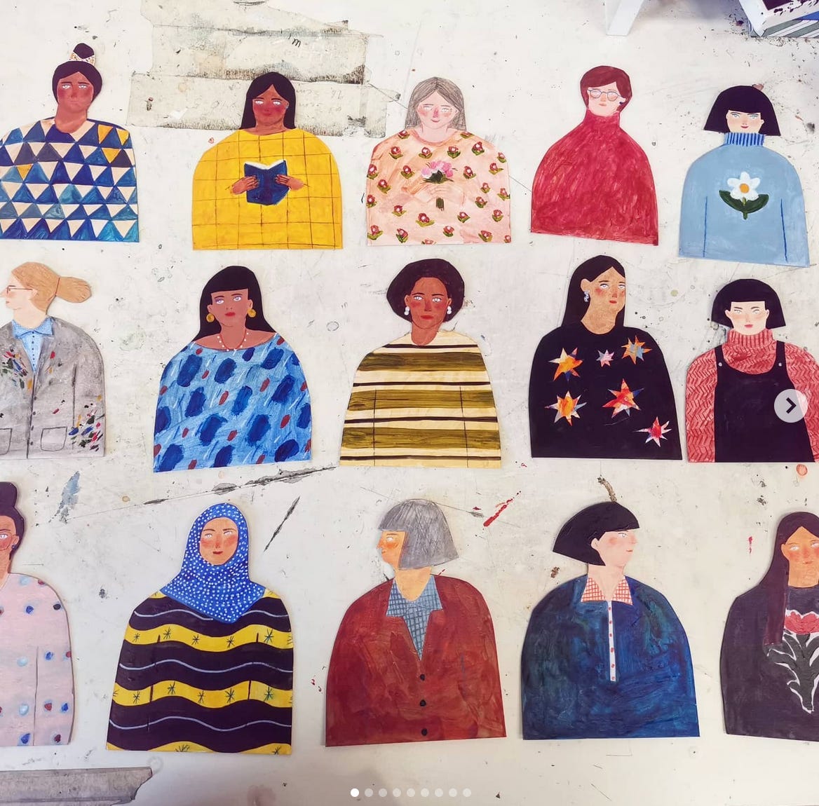 fifteen cardboard women, painted in different colourful outfits. 