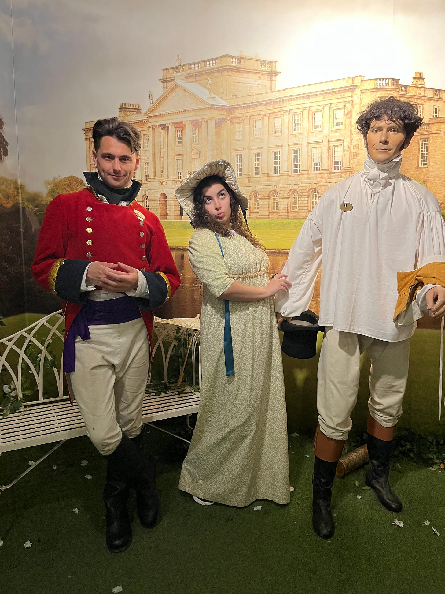 a man dressed in a red coat (Mr. Wickham), an individual in the middle dressed as a woman from Austen times (me), and a dummy dressed in a white tunic and pants intended to look like mr darcy
