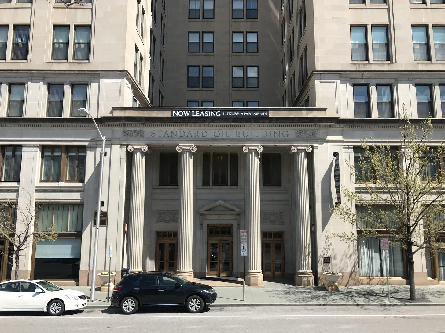 This is a street-level photograph of the front of Baltimore's Standard Oil Building. "STANDARD OIL BUILDING" is engraved above the entrance, which also includes four classical pillars.