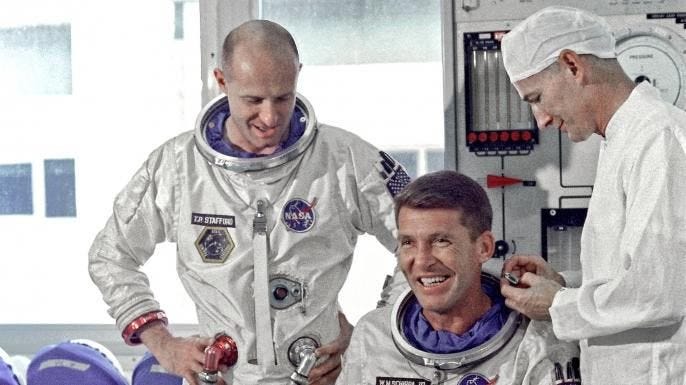 Astronauts Walter M. Schirra Jr. (seated), command pilot, and Thomas P. Stafford, pilot, Gemini 6 prime crew, go through suiting up exercises in preparation for their forthcoming flight. (Credit: Public Domain)