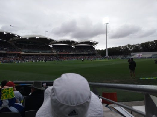 A man in a hat ahead of me, a low view of the pitch ahead of him