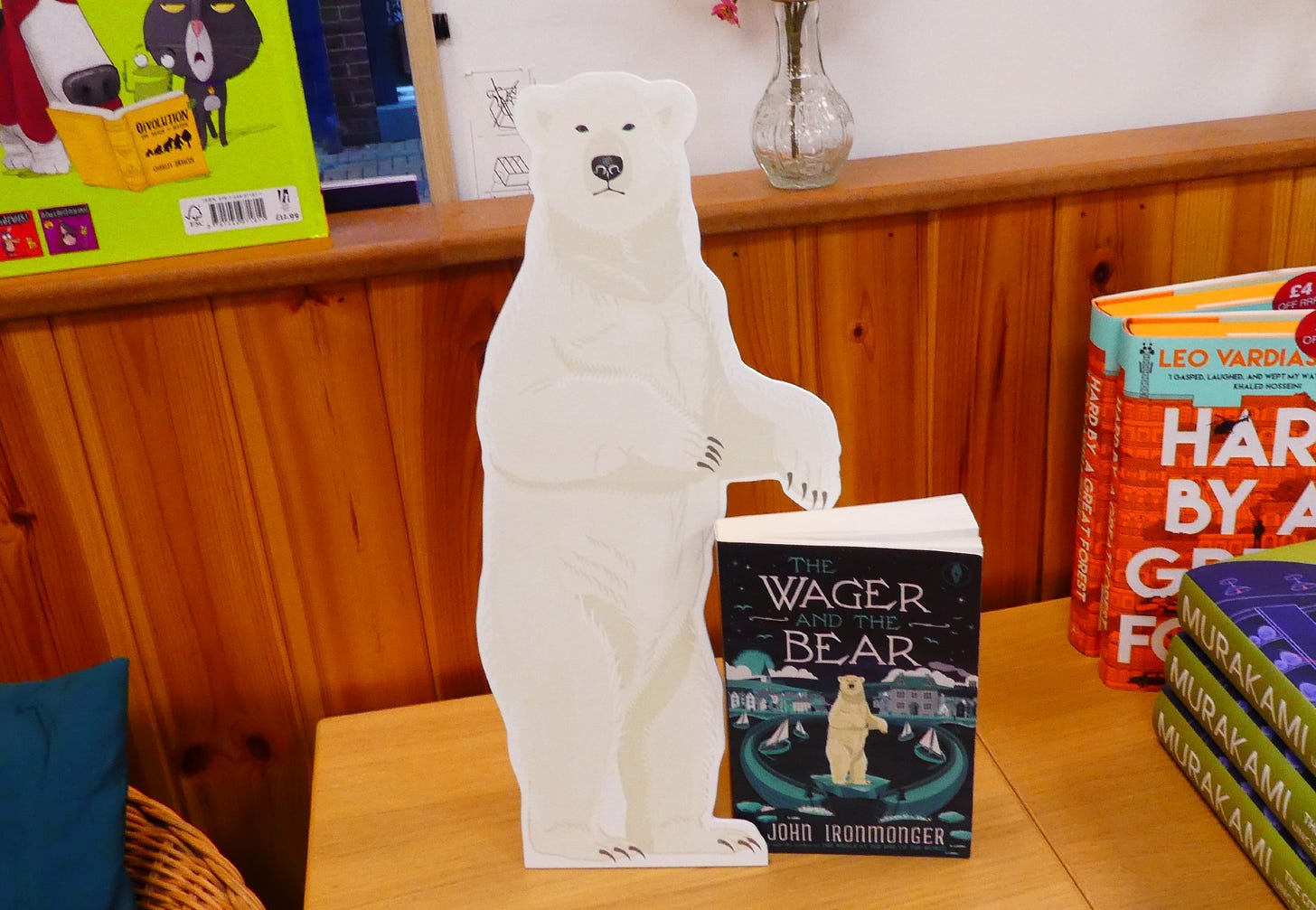 Image of a cardboard stand of a polar bear, around 18-24 inches high, with a book standing next to it, The Wager and the Bear featuring the same polar bear image on the cover.