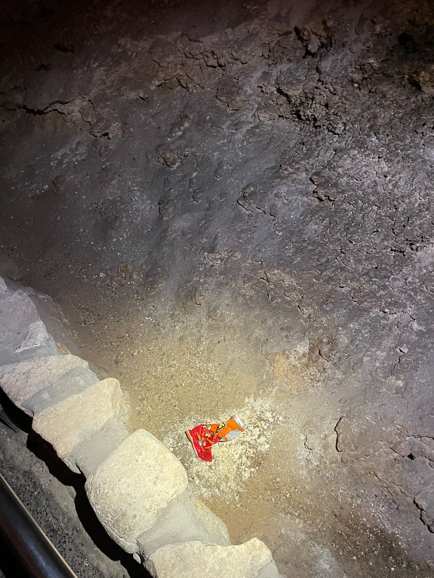 A discarded, crumpled-up bag of snacks on a cavern floor