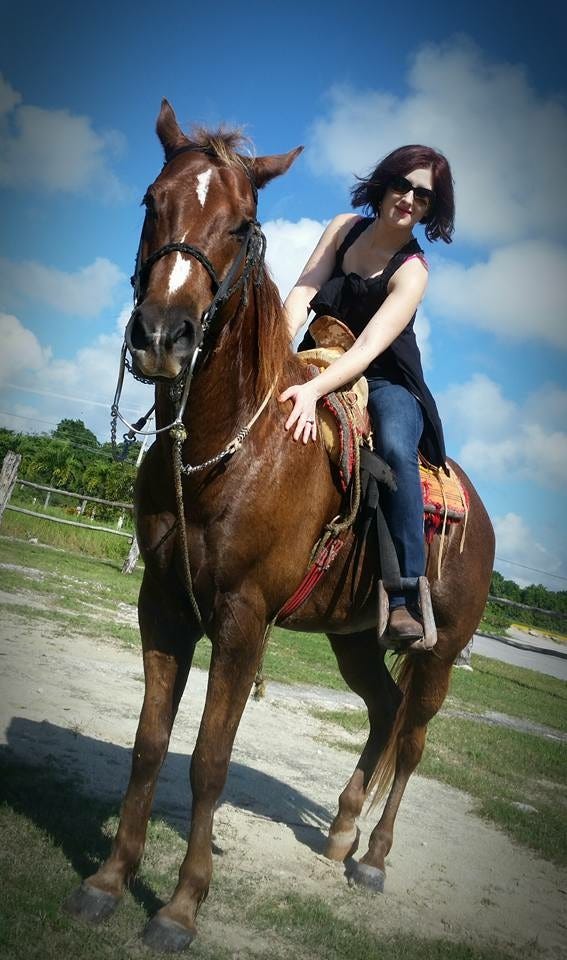 Lyric on a beautiful brown horse in a western saddle. 